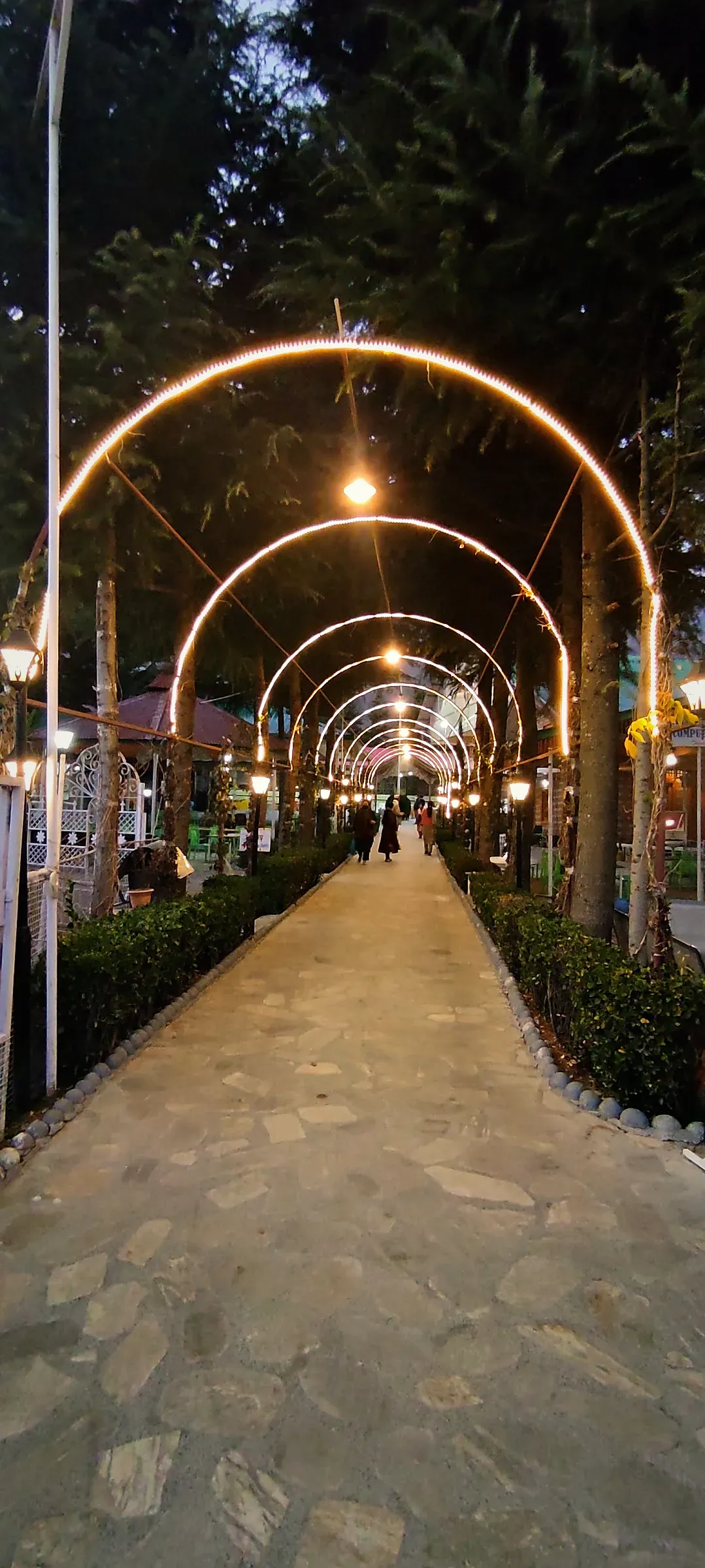A walkway under a tunnel of lit arches at dusk
