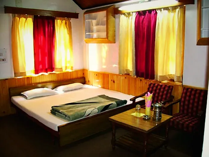 A cottage room with bright curtains, a double bed and armchairs